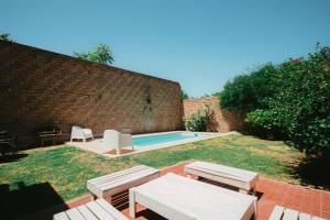 un patio trasero con piscina, sillas y una pared de ladrillo en Casa Quinta Seccion en Mendoza