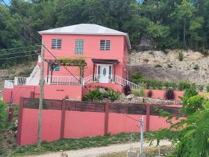 uma casa cor-de-rosa com uma vedação à frente. em Mount Joy Getaway em Parham