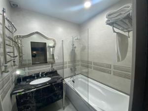 een badkamer met een wastafel, een bad en een spiegel bij Sunrise Apartments in Doesjanbe