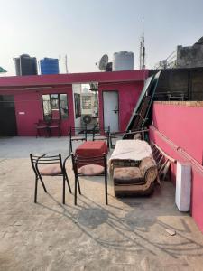 eine Gruppe von Stühlen und Betten außerhalb eines Gebäudes in der Unterkunft Thomas Home Stay in Agra