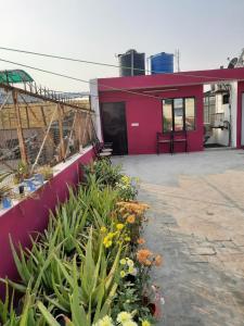 Un bâtiment rouge avec des fleurs devant lui dans l'établissement Thomas Home Stay, à Agra