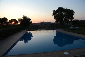 a swimming pool with a sunset in the background at Hotel Cigarral el Bosque in Toledo