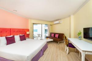 a bedroom with a bed and a desk and a tv at Bella Villa Metro in Pattaya North