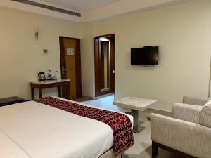 a hotel room with a bed and a couch and a television at Anukulas Residency - Vellore in Vellore