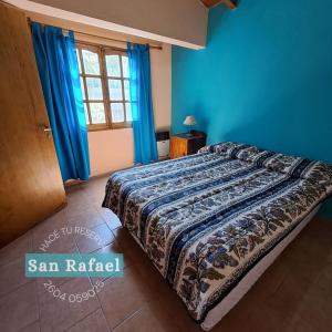 Un dormitorio con una cama con paredes azules y una ventana en Departamento Céntrico en San Rafael