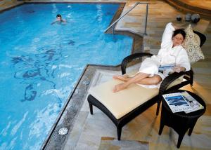 hotel & chalet madlochBlick في ليش ام ارلبرغ: امرأة جالسة على كرسي أمام حمام السباحة