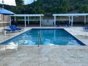 una piscina con sillas azules y sombrilla en Seamist villa @Oceanpointe Lucea comfy 2BR w/pool gym & parking, en Lucea
