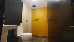 a bathroom with a toilet and a yellow door at Departamentos fresno! Una excelente opción in Toluca