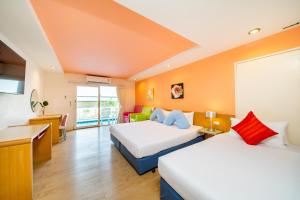 a hotel room with two beds and a desk at Best Bella Pattaya in North Pattaya