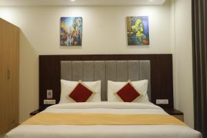 a bedroom with a large bed with two paintings on the wall at Hotel Gurugram in Gurgaon