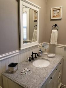 een badkamer met een wastafel en een spiegel bij Colonial Cottage Getaway in Atascadero