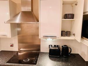 eine Küche mit weißen Schränken und einem Kühlschrank aus Edelstahl in der Unterkunft High vibes home in Chelmsford