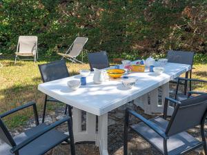una mesa blanca con sillas y cuencos. en Villa La Trinité-sur-Mer, 5 pièces, 8 personnes - FR-1-477-6 en La Trinité-sur-Mer