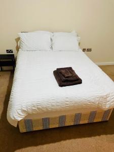 a white bed with a brown towel on it at High vibes home in Chelmsford