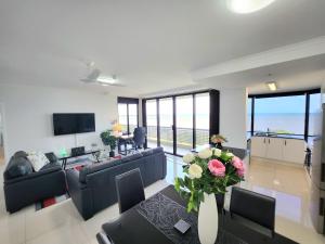 a living room with a couch and a table with flowers at Cairns Luxury Seaview Apartment in Cairns