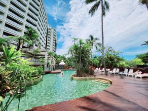 a swimming pool in a resort with palm trees and buildings at Cairns Luxury Seaview Apartment in Cairns