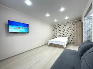 Un dormitorio con una cama y un televisor en una pared. en Квартира DOSTYK MALL, Университет, en Petropavlovsk