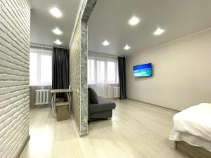 1 dormitorio con sofá y TV en la pared en Квартира DOSTYK MALL, Университет, en Petropavlovsk