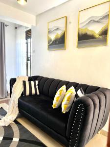 a black couch in a living room with pillows at Dees apartment Milimani - Fast Wifi & Secure Parking in Kisumu