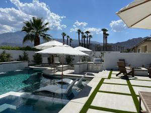 a swimming pool with umbrellas and chairs in a house at NEW Listing in La Quinta – Stunning Vacation Home! in La Quinta