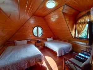 a bedroom with two beds in a wooden cabin at Rong Yuan Gu Homestay in Nanzhuang