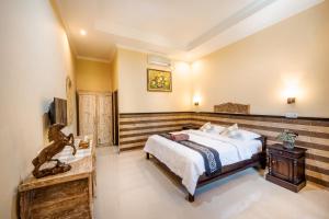 サヌールにあるGria Umasari Sanurのベッドとテレビのある寝室