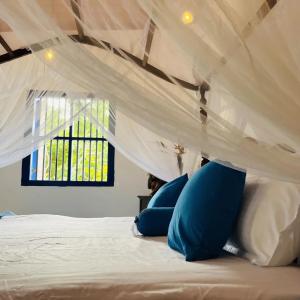 a bed with blue pillows under a white canopy at Sriyan Villa in Beruwala