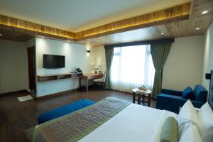 ein Hotelzimmer mit einem Bett und einem TV in der Unterkunft Mount Magnolia Boutique Hotel & Spa in Pelling