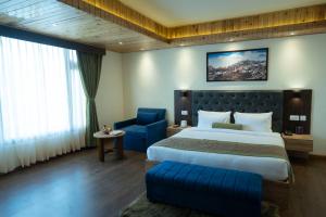 a bedroom with a large bed and a blue chair at Mount Magnolia Boutique Hotel & Spa in Pelling