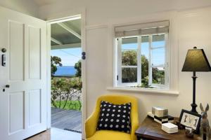 a living room with a yellow chair and a table and windows at Minke Whalers Cottage circa 1926 Hyams Beach in Hyams Beach