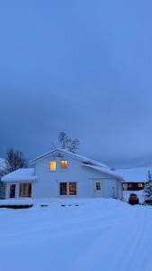 a white house in the snow at night at Mountainside Lodge - Breivikeidet in Tromsø