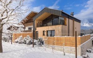 una casa en la nieve con una valla en Haus Sonnblick Chalet, en Reith im Alpbachtal