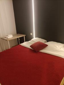 a room with a bed with a red blanket and a table at PETiT MULHOUSE 201 in Mulhouse