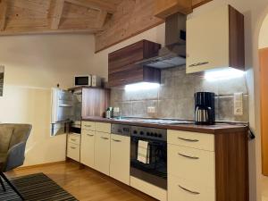 a kitchen with white cabinets and a stove top oven at Appartement Thurnbach in Aschau