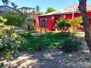 une maison rouge avec un jardin en face dans l'établissement Casa Minha Backpackers Hostel, à Dili