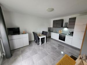 cocina con armarios blancos, mesa y sillas en Apartement Luna, en Petrčane