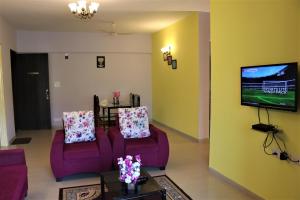 a living room with two purple chairs and a tv at PORTOFINO in Lavasa