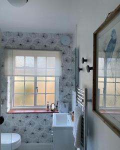 a bathroom with a window and a white sink at Cottage Number 5 in Southwold - Charming cottage gardens in Southwold