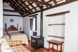 Casas Rurales Tugasa Castillo de Castellar في كاستيلار دي لا فرونتيرا: غرفة نوم بسرير وموقد خشب