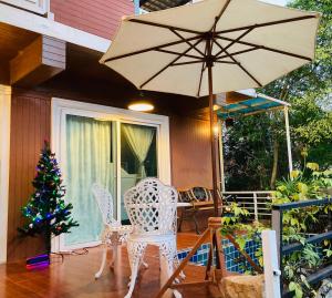 a porch with a table and an umbrella and a christmas tree at lemoon house khaoyai in Nong Nam Daeng