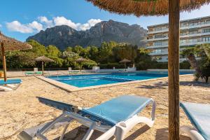 a swimming pool with a beach chair and an umbrella at Townhouse Sonrisa by Homevillas360 in Artá