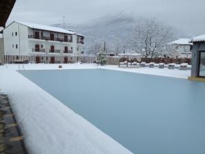 a swimming pool covered in snow with a house at Mont Helmos Hotel in Klitoria