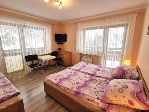 a bedroom with a bed and a desk and windows at ,,u Uli'' kwatery i domek in Piwniczna-Zdrój
