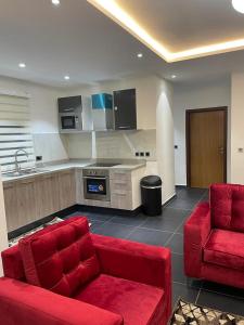 Park D-plus Apartments Cantonments في آكرا: غرفة معيشة بها كنب احمر ومطبخ