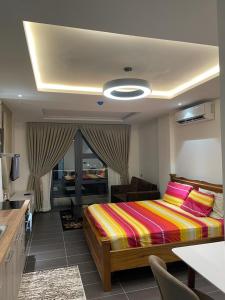 um quarto com uma cama com um cobertor listrado colorido em Park D-plus Apartments Cantonments em Accra