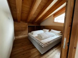 a bed in a small room with a wooden ceiling at YETI Design mountain apartments in Valdidentro