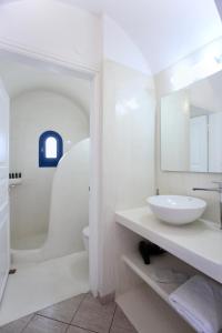 a white bathroom with a sink and a toilet at Pergeri Apartments in Imerovigli