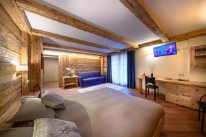a bedroom with a large bed and a blue couch at Hotel Ambrosini in Aprica