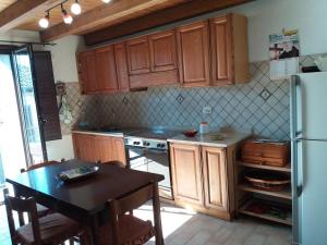 a kitchen with wooden cabinets and a table and a refrigerator at La Nicchia in Gerace