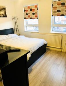 a bedroom with a bed and a desk and two windows at Nice Double Room London Rental in London